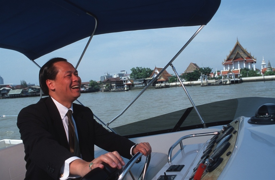Banthoon Lamsam, Thai Farmers Bank Plc President and Chairman of the Thai Bankers Association, drives his bank's motor cruiser boat on his way to a meeting with the Governor of the Bank of Thailand. Banthoon Lamsam has been credited with turning around the fortunes of his Thai Farmers Bank after the economic crash of 1978. US-educated (Harvard MBA), his management style is considered iconoclastic by traditional Thai business standards, but is paying off. His is the only bank likely to make a profit in 2000.